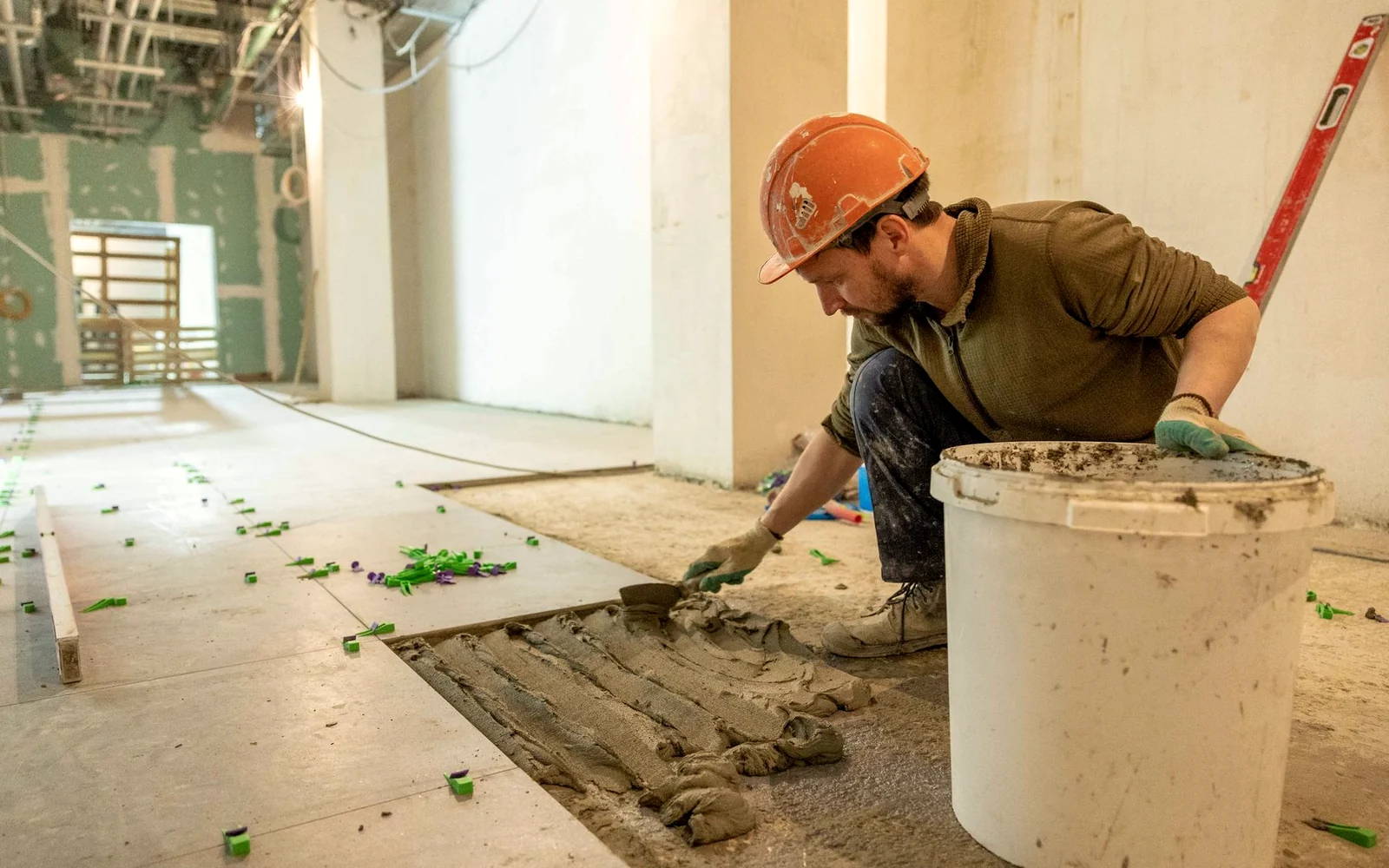 Handwerker verlegt großformatige Bodenplatten in einem Gewerberaum