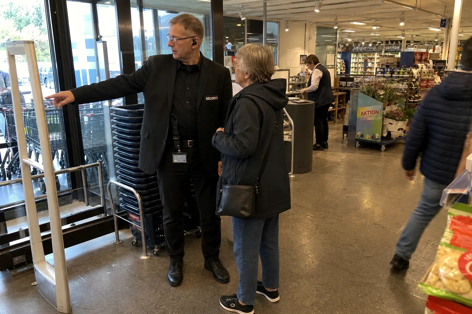 Mitarbeiter im Eingangsbereich eines Marktes im Gespräch mit einer Kundin