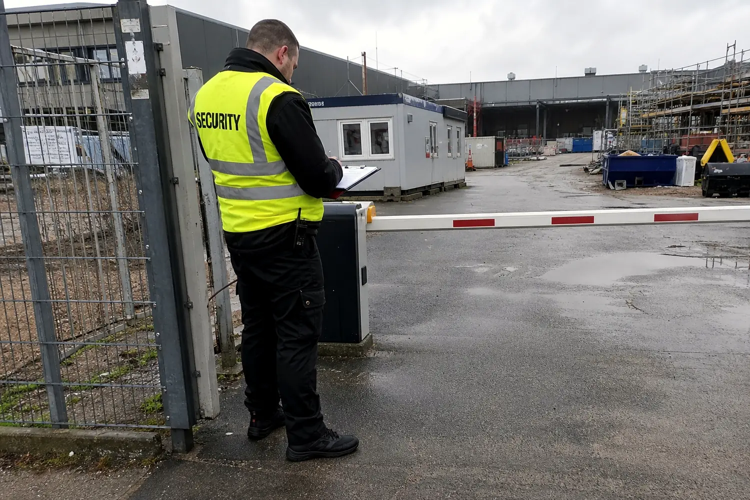 Mitarbeiter in Warnweste am Zufahrtstor einer Baustelle